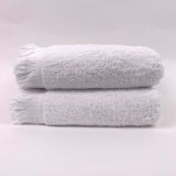 Two white towels stacked on a light gray background
