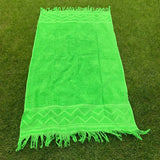 Green towel with fringes on a green grass background