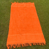Orange towel with fringes on a grassy background