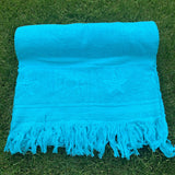Turquoise towel with fringes on a grassy background