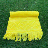 Yellow towel with zigzag pattern and fringes on grass