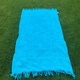 Blue towel with tassels on a grassy background