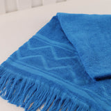 Turquoise towel with fringes on a white surface