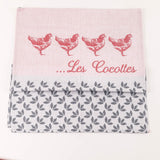 Fabric with red chicken illustrations and 'Les Cocottes' text on a pink background, featuring a leaf pattern at the bottom.