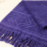 Purple towel with geometric pattern and fringes on a white background