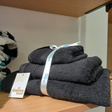 Stack of Black towels on a wooden shelf with a visible brand tag.