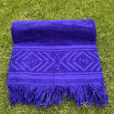 Blue towel with geometric pattern and fringes on grass