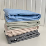 Stack of folded clothes in various colors on a white surface with a light gray background