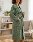 Woman wearing a green bathrobe holding a mug in a cozy living room.