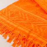 Close-up of an orange towel with fringes on a white background