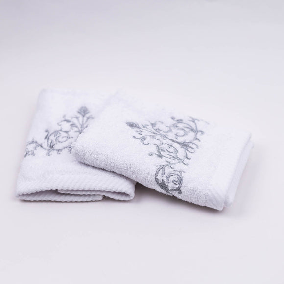 Two white towels with decorative embroidery on a light gray background