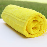 Rolled yellow towel on a white surface with a green background