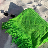 Green towel with fringes on a sandy surface
