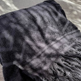 Black textured towel with fringes on a neutral background