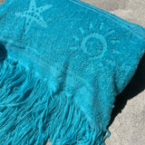Blue towel with star and moon designs on a concrete surface