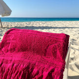 Fuchsia towel with fringes on a beach chair by the ocean