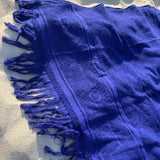 Blue towel with fringes on a sandy surface