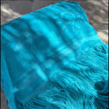 Close-up of a blue towel with fringes on a textured surface
