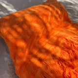 Orange beach towel with fringes on a sand surface