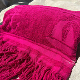Pink towel with fringes on a sandy surface